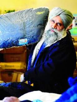 Organizer Mike Sandhu hands out men's coats at the clothing giveaway Saturday in Tracy at the Larch Clover Community Center. (MICHAELMcCOLLUM/The Record)
