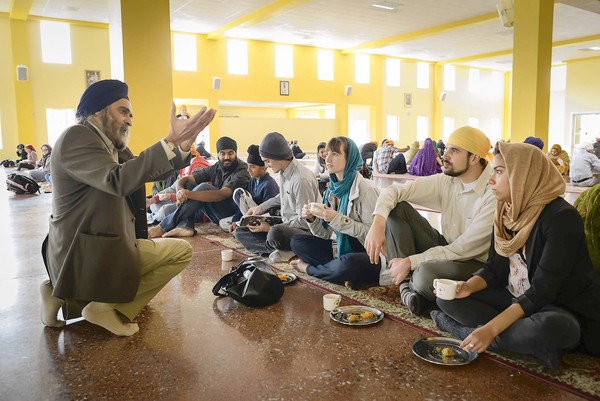 "UC Santa Cruz instructor Nirvikar Singh, left, speaks to Hannah Elston, center, Kevin Deutsch, second from right, and Virginia Perez, right, during lunch at the Sikh Gurdwara in San Jose." (David Butow, For The Times / October 21, 2012)