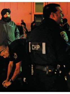 "Karm Bains, left, looks on Saturday night as law enforcement personnel investigate two stabbings following a meeting at a Sikh temple in Yuba City." (Nate Chute/Appeal-Democrat)