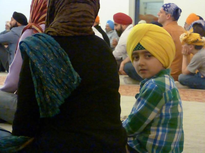 A child takes notice of the camera during the interfaith evening at the Sikh Temple of Utah, March 6 (Photo credit: Andalin Bachman. Source: Salt Lake Interfaith Roundtable Facebook page)