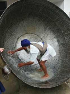 "What is he panning for? A man cleans a huge pan to prepare a non-alcoholic drink during celebrations of Hola Mohalla festival at Anandpur Sahib, India. The Hola Mohalla festival is celebrated during the Hindu religious festival of Holi, marking the congregation of Sikh devotees from all over the country. Photograph: Ajay Verma/Reuters" (source: The Guardian)