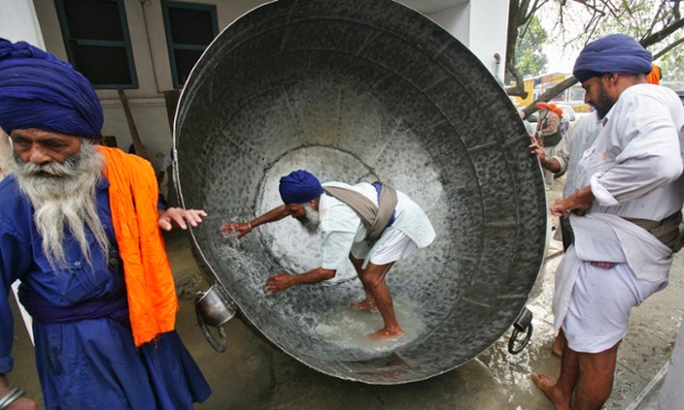 "What is he panning for? A man cleans a huge pan to prepare a non-alcoholic drink during celebrations of Hola Mohalla festival at Anandpur Sahib, India. The Hola Mohalla festival is celebrated during the Hindu religious festival of Holi, marking the congregation of Sikh devotees from all over the country. Photograph: Ajay Verma/Reuters" (source: The Guardian)