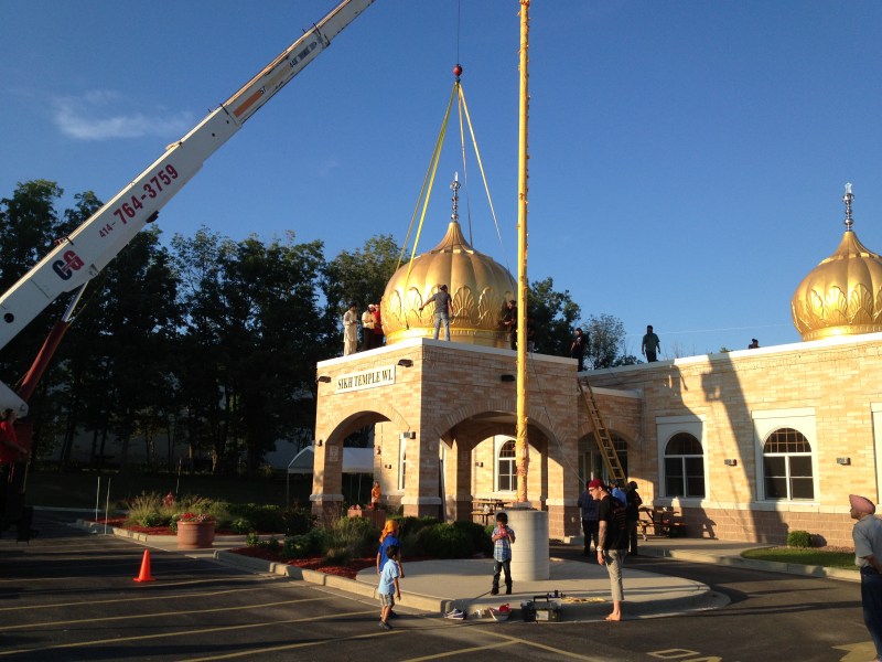 Workers install seven domes at the Sikh Temple of Wisconsin in Oak Creek earlier this month, as tributes to the lives lost in last year's shooting rampage by a white supremacist. (Source:  WISN-TV)