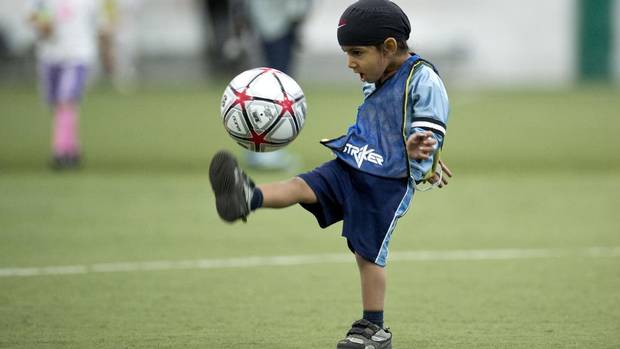 "Harshaan Ahluwalia, 2, dribbles a soccer ball during a friendly soccer match in solidarity with young players who wear turbans Saturday, June 15, 2013 in Montreal. Quebec's soccer federation announced it is ending its much-criticized turban ban Saturday." (Photo credit: Paul Chiasson | THE CANADIAN PRESS. Source: The Globe and Mail.)