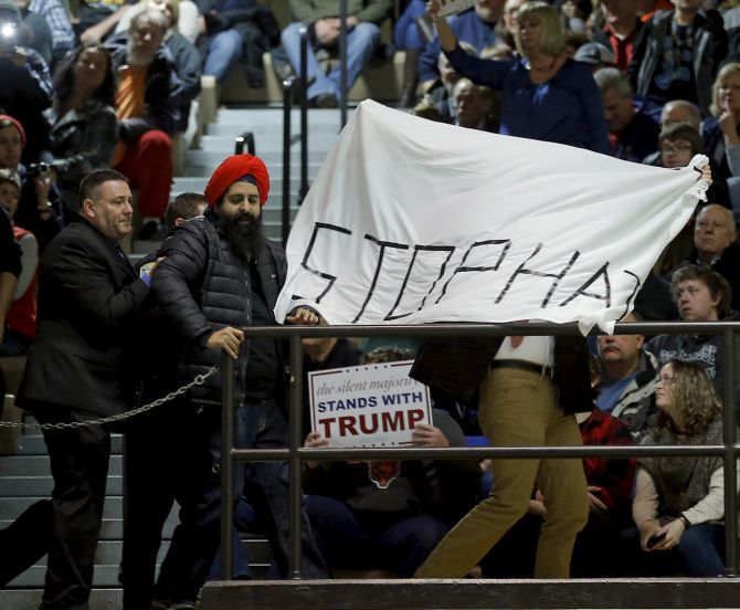Protesters are escorted out of a U.S. Republican presidential candidate Donald Trump campaign event in Muscatine